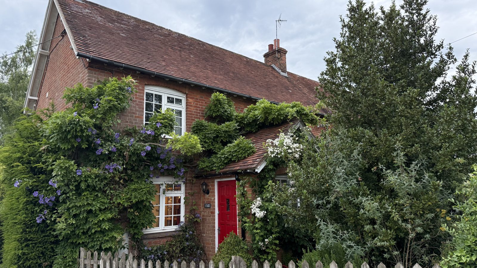 The Cottage — a period house with a red front door behind a picket fence